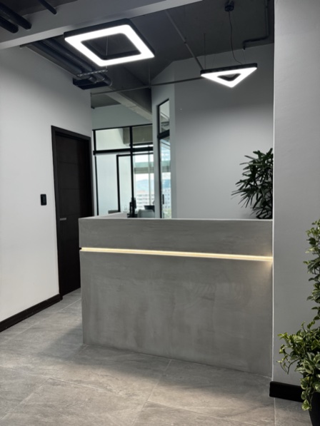 Recepción de Asesoria Global en Zona 10, Ciudad de Guatemala — mostrador de concreto pulido con iluminación LED moderna